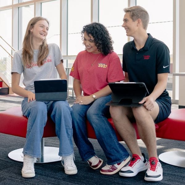 Students seated on a bench on their laptops