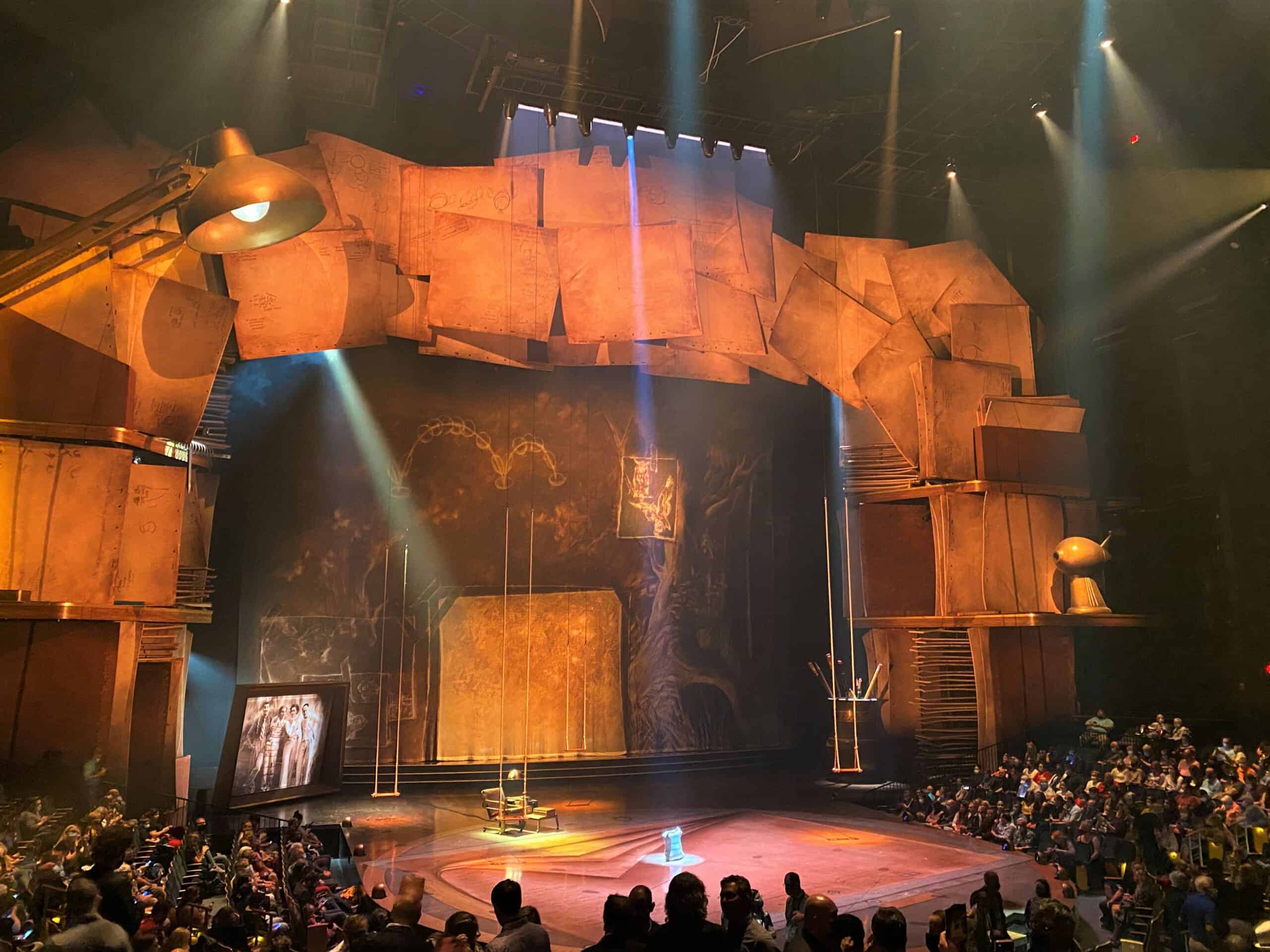 Cirque du Soleil Disney Springs - Drawn to Life Stage resembles an animator's desk. A large desk lamp is on one side of the theater, towering multiple stories. A frame of massive blank papers used to drawn animation make the frame of the stage as other elements of a desk are larger than life props throughout the stage. 