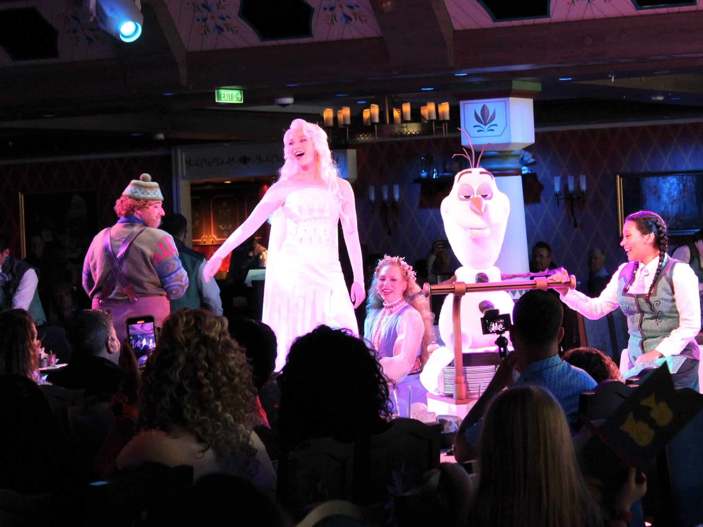 Elsa performs on a stage with an Olaf character at Arendelle Frozen Dining Adventure on Disney Wish