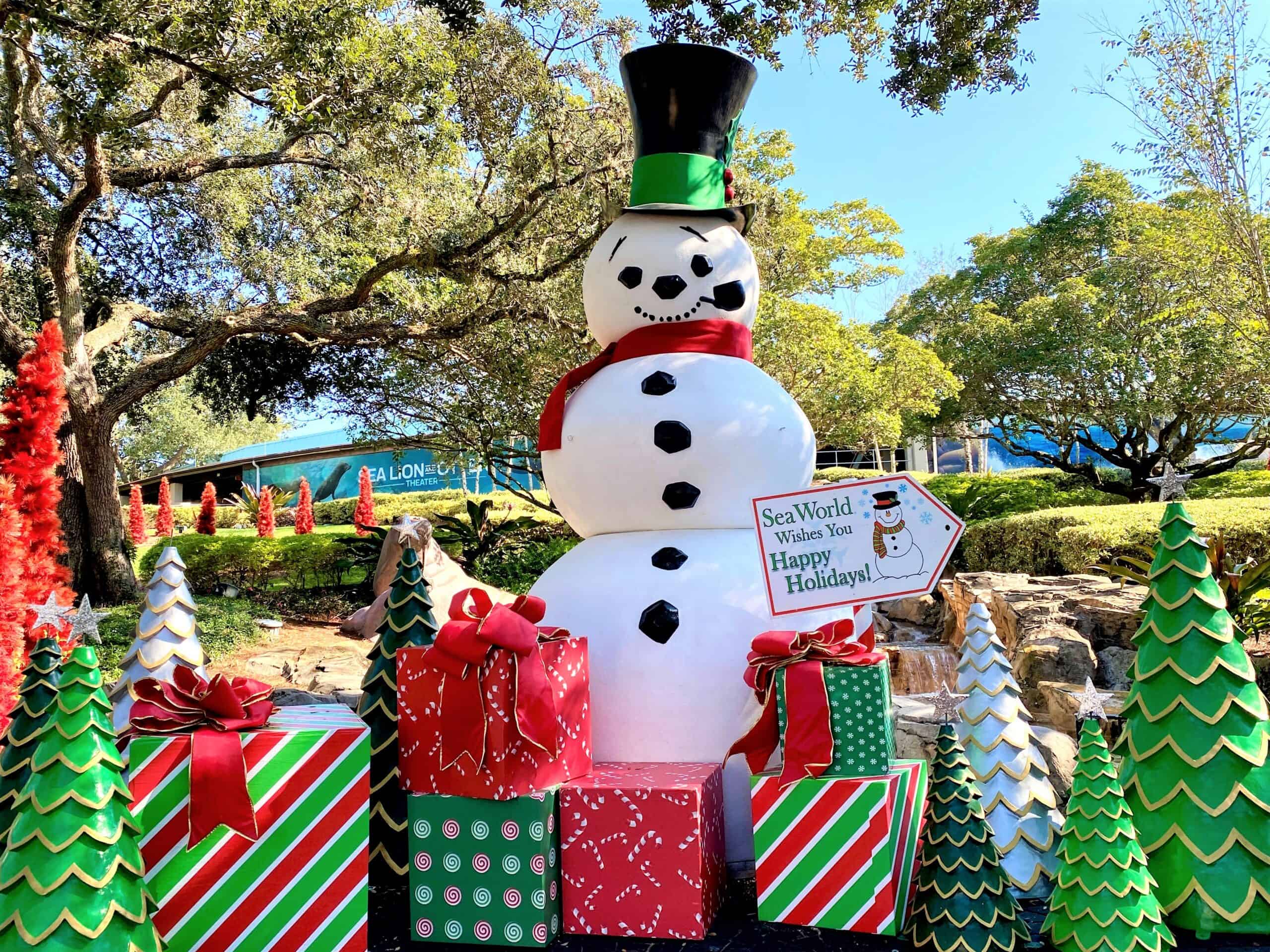 Photo opportunities during SeaWorld Orlando's Christmas Celebration include a large white snowman wearing a black top hat and surrounded by large Christmas present props in red and green wrapping paper, and red and green Christmas trees