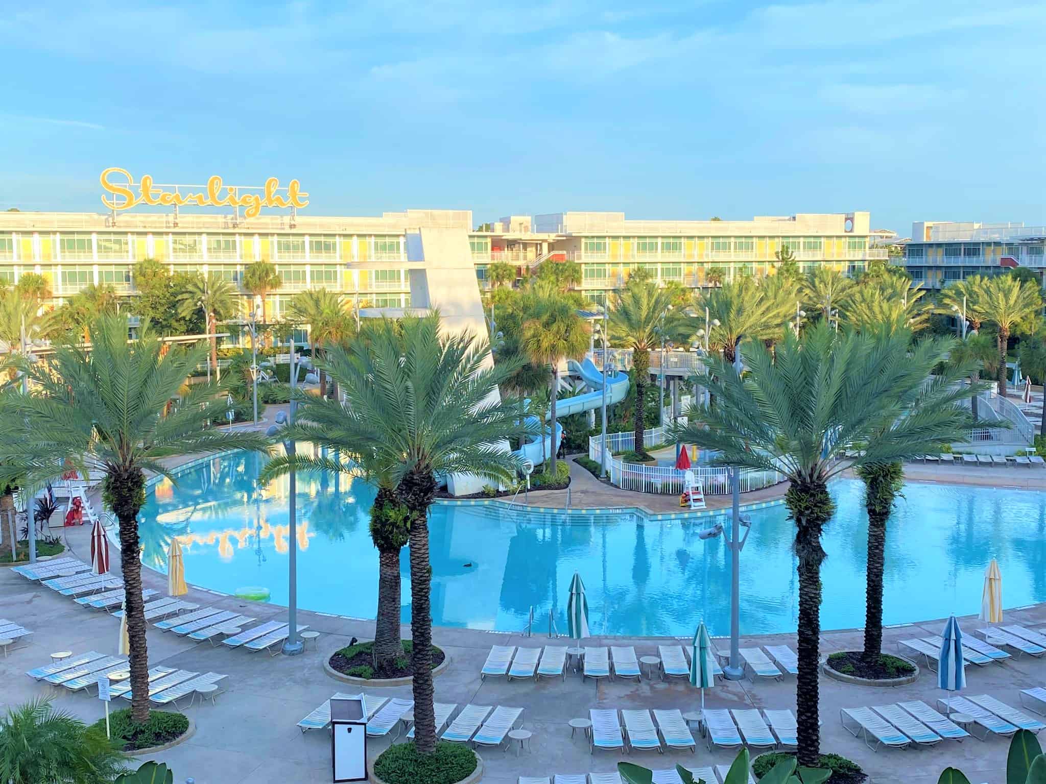 Universal Cabana Beach Resort Pool is surrounded by the hotel buildings and features palms trees, plenty of lounge chairs, and a curving waterslide
