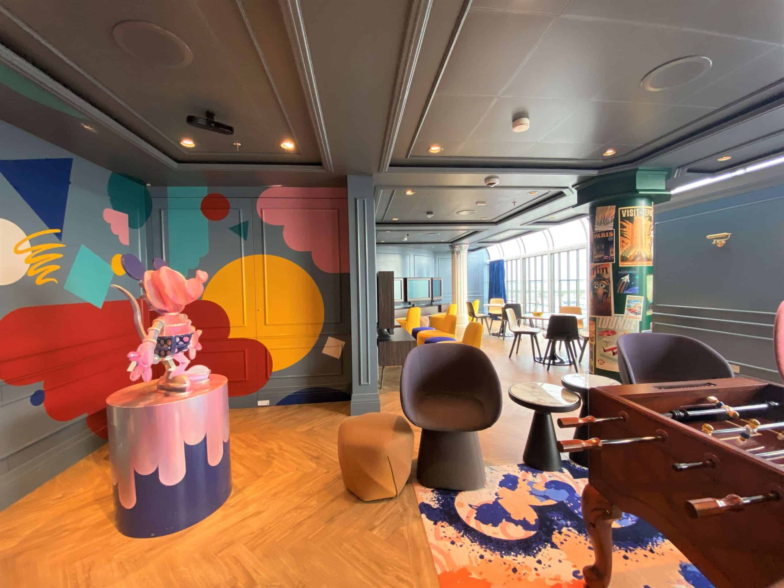 Vibe Teens' Club on Disney Wish with foosball table and brightly colored paint splatters on the wall to resemble an artists' loft