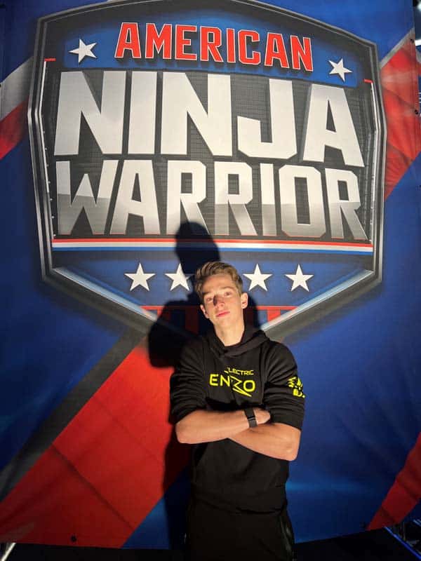 Enzo poses in front of American Ninja Warrior sign