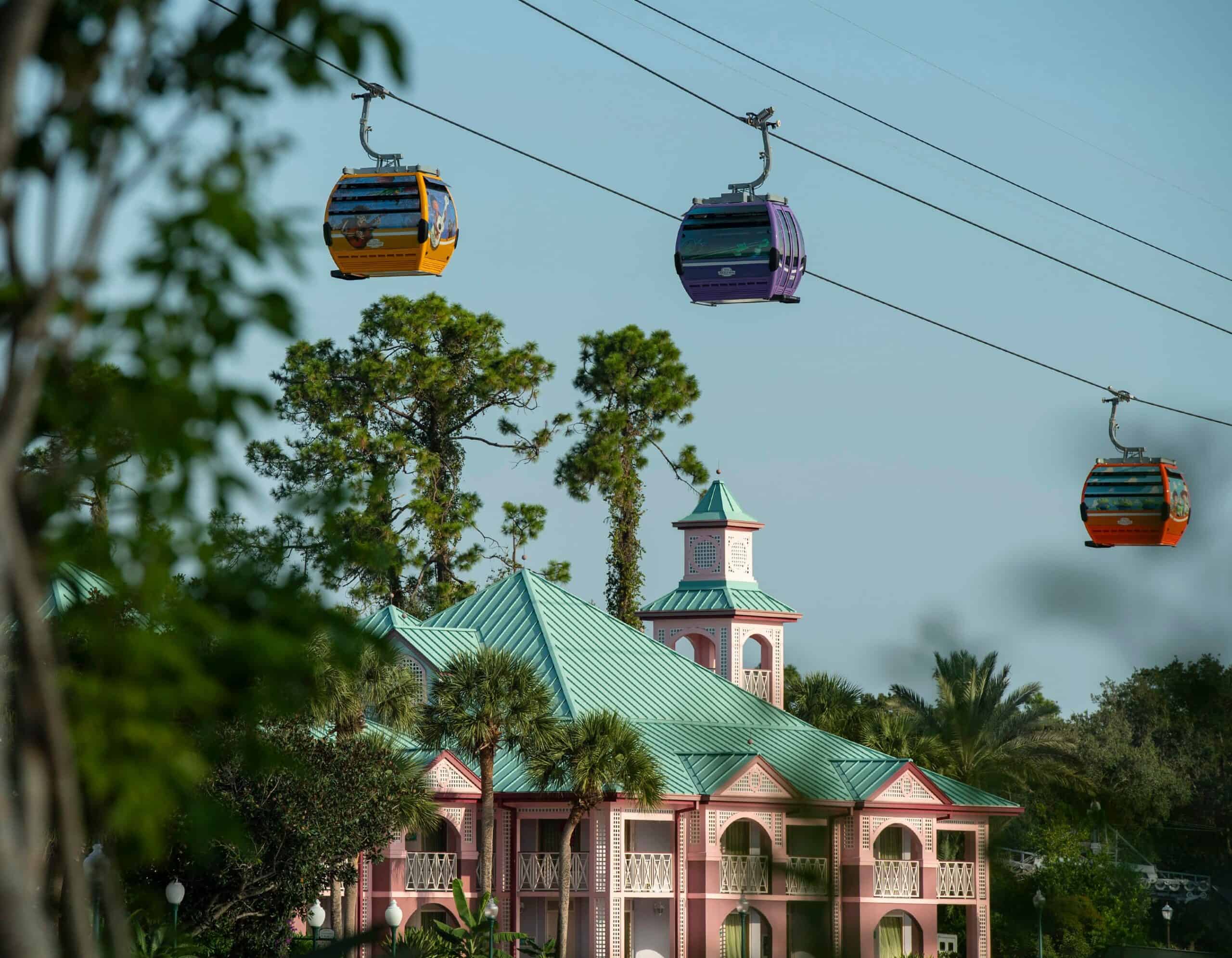 Three Disney Skyliner gondolas glide along their cables above Disney's Caribbean Beach resort