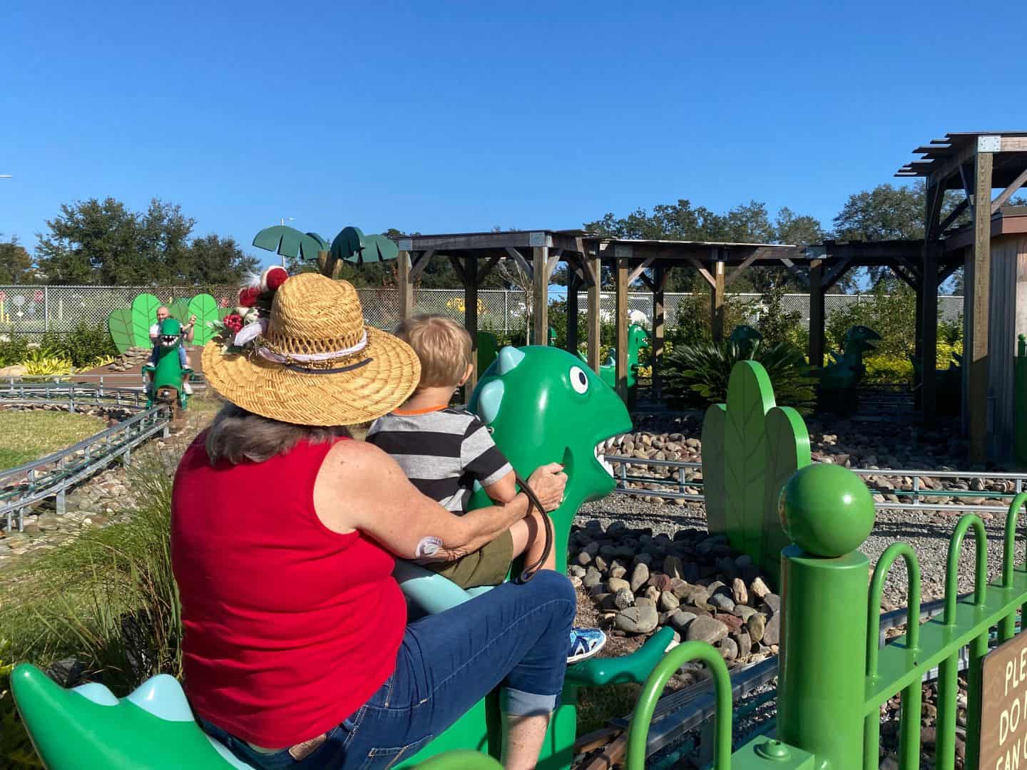 A grandmother and her son ride together on Dinosaur Adventure Ride at Peppa Pig Theme Park