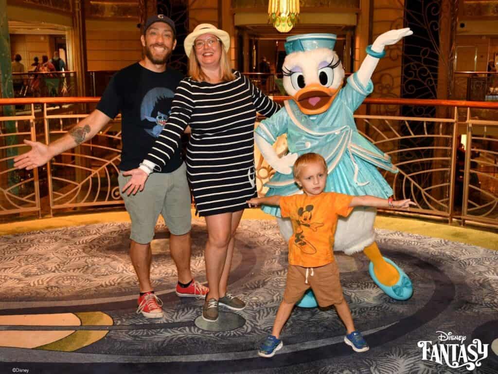 Daisy Duck in 25th Anniversary Costume Disney Fantasy Cruise greets a family of two adults and one child