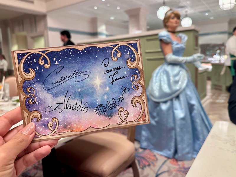 photographer holding disney character autograph card with cinderella in the background, at 1900 Park Fare dinner