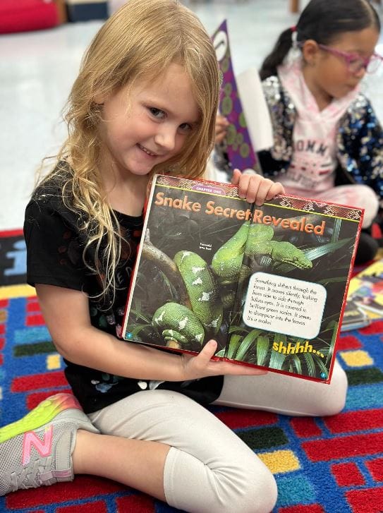 stopping the summer slide, girl showing her book about snakes