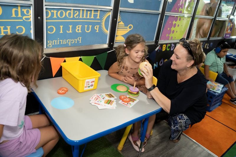 a teacher playing with students inside Paige the LIteracy Bus from Hillsborough County Public Schools