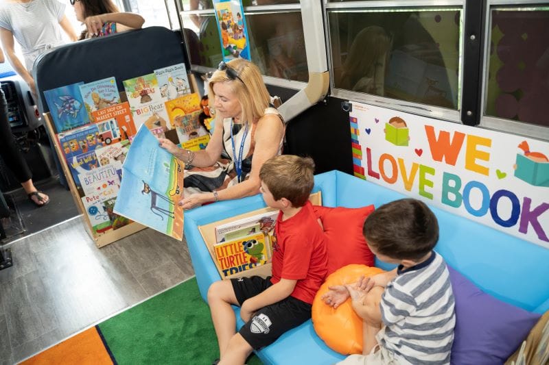 inside Paige the LIteracy bus, a teacher reads to students