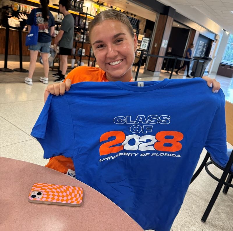 The author's daughter holds up her Class of 2028 shirt for college