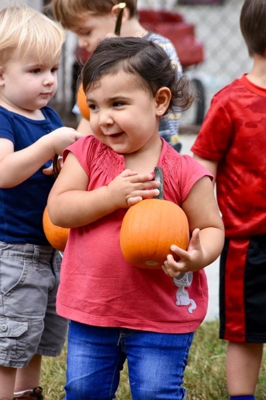 girl holding a pumpkin at Watermelon Swim's Fall Festival