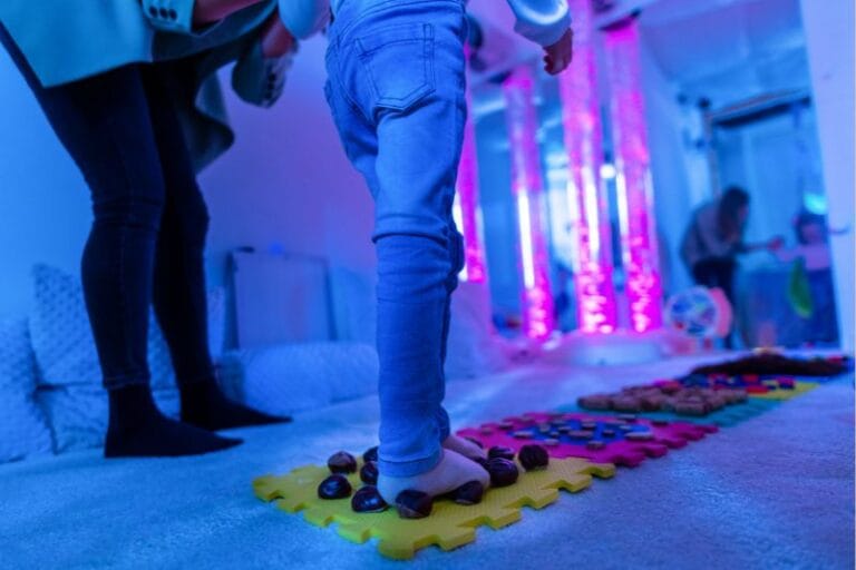 Therapist helping a young child Texture walk, sensory exploration, motor skills - getty images