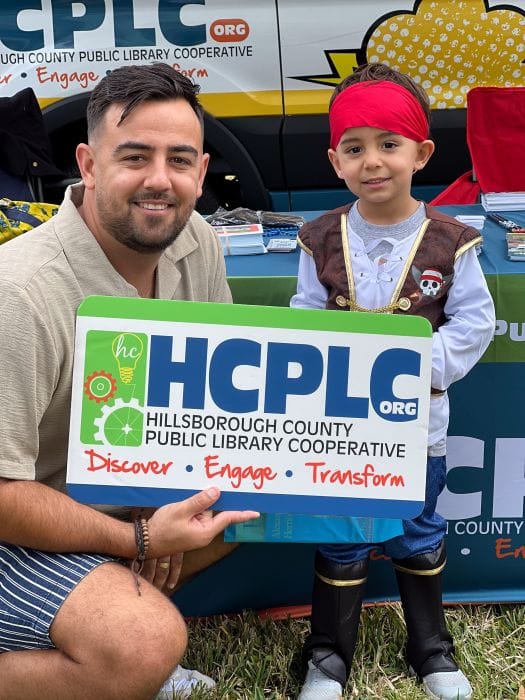 Family posing with library card for National Library Week