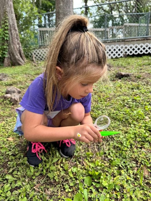 student inspecting a bug outside at Corbett Prep