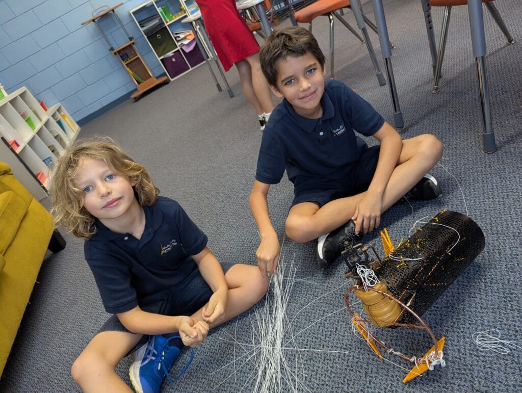 Two students seated in front of science project