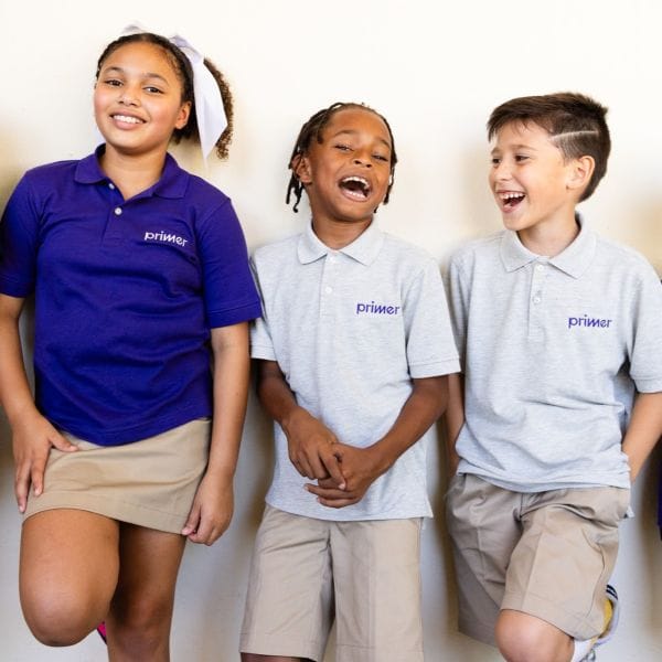 Students laughing and posing against a wall