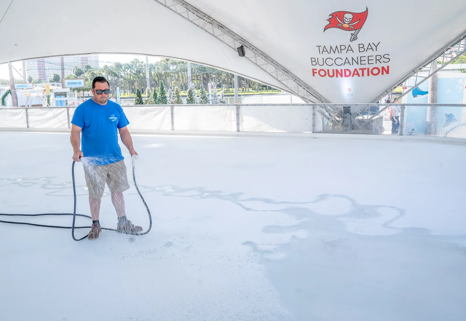man using water hose to make ice for outdoor ice rink at Winter Village in Tampa.