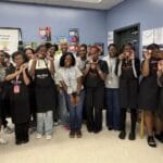 Young girls standing together wearing aprons in a classroom after creating their own body scrub