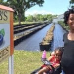A mother and her child standing in front of a blueberry field for blueberry season at Bob's Berries