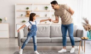 Dad and daughter dancing together in a light colored living room