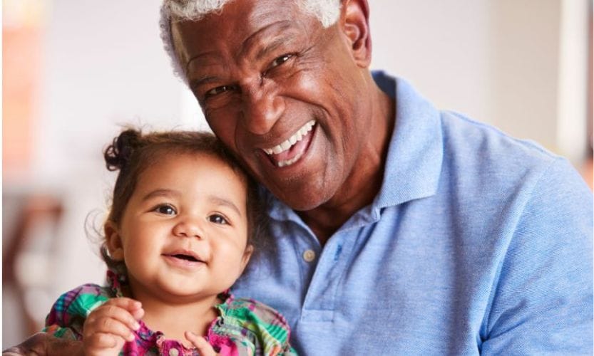 and older gentleman smiling big while holding a happy younger child