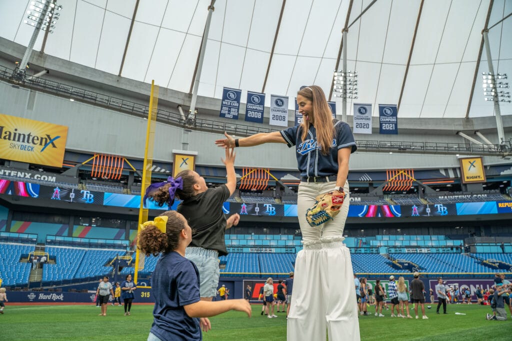 Tampa Bay Rays home games at Tropicana Field. Kids on field with stilt walker during Family Fundays game.