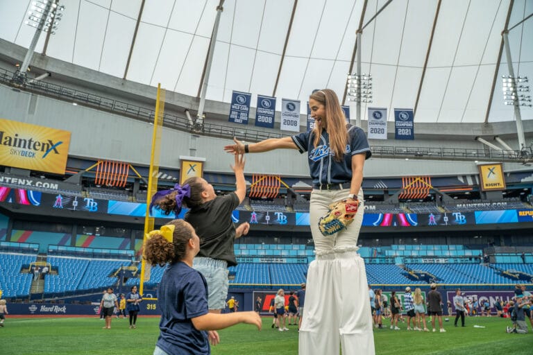 Tampa Bay Rays home games at Tropicana Field. Kids on field with stilt walker during Family Fundays game.