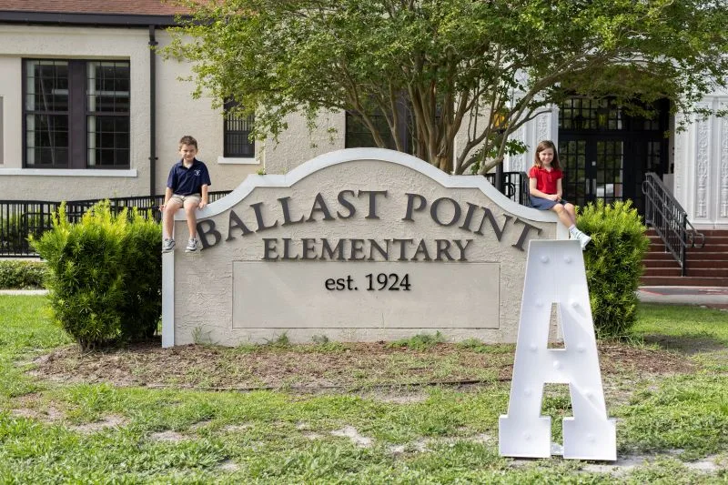 Students sitting on Ballast Point sign.