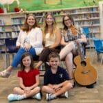 Teachers and students seated together in media center.