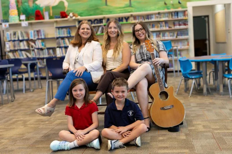 Teachers and students seated together in media center.