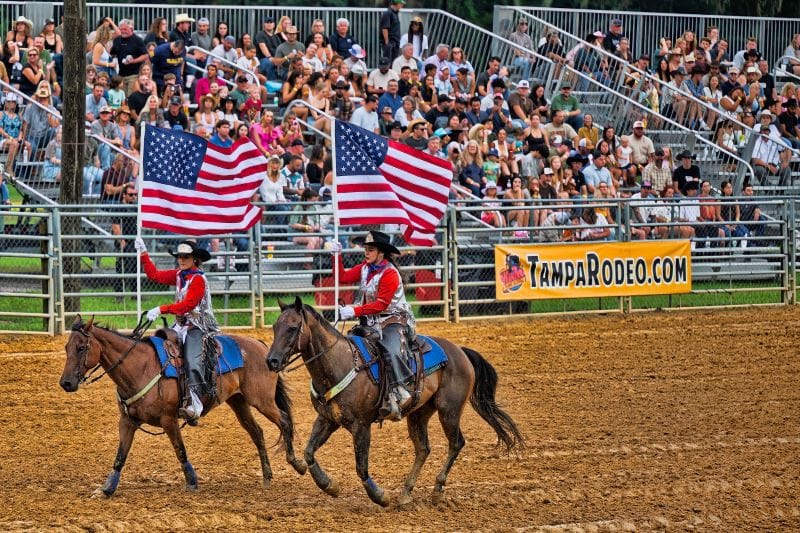 Horse riders carrying flags at the Tampa Bay Rodeo and Family Fest